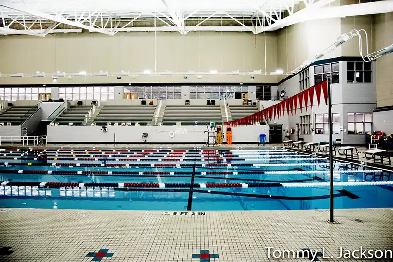 A string of red backstroke flags over the lanes, with deck benches and a lifeguard stand at the right