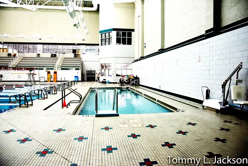 The smaller pool with steps into the water, set into the tiled deck below a tall white wall