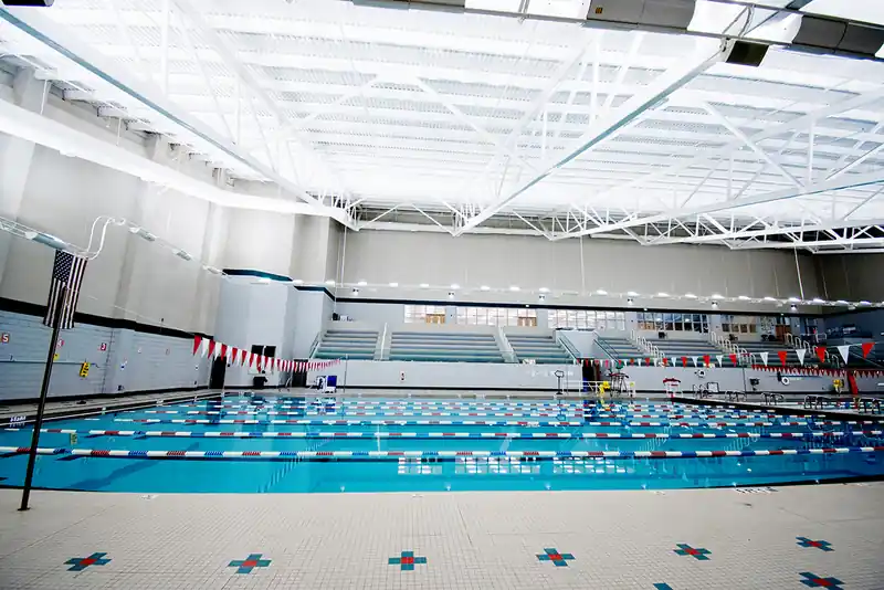 Tiered spectator seating behind the lanes, with an American flag on a pole at the left and a white roof truss overhead