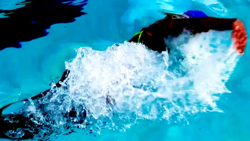 A butterfly swimmer breaking the surface in a burst of white water